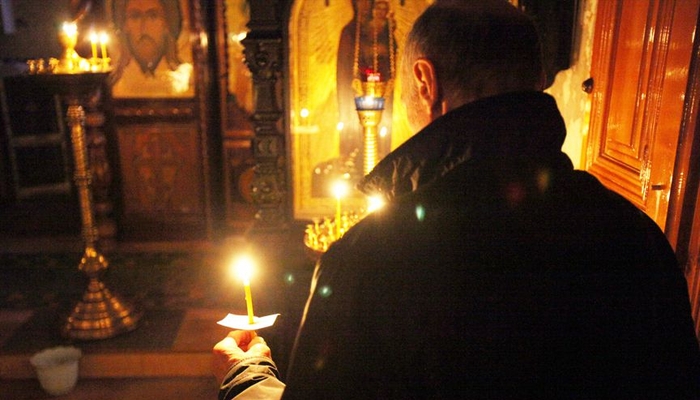 Чоловік зі свічкою молиться в церкві
