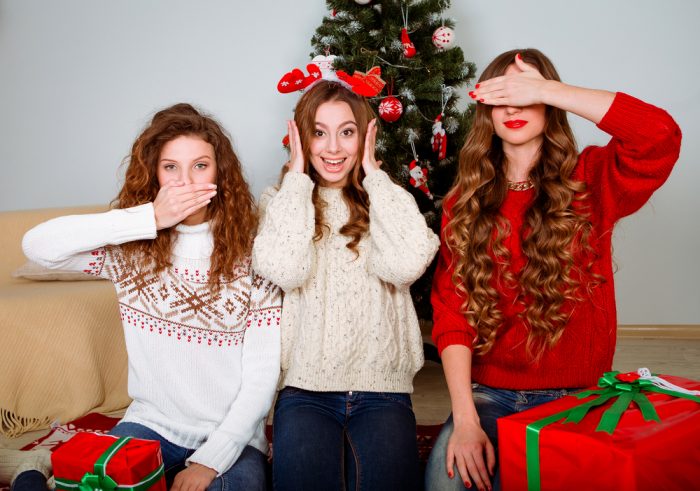 Дівчата біля новорічної ялинки в білих светрах
